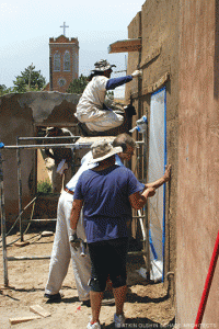 Shawn Evans (standing, center) tries his hand at plastering.