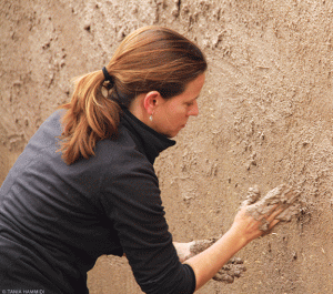 Jamie Blosser practices mud-plastering on a wall. 
