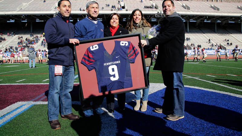 Bagnoli poses with his wife and three kids as he's presented with a framed jersey. The 9 is for the number of Ivy League championships he won at Penn.