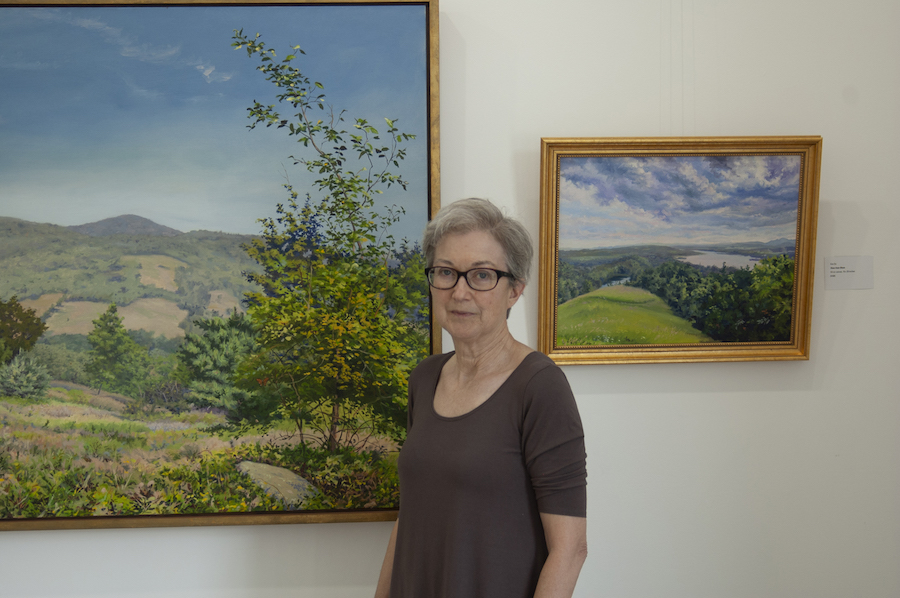 Bepe stands in front of two landscape paintings by Kim Do 