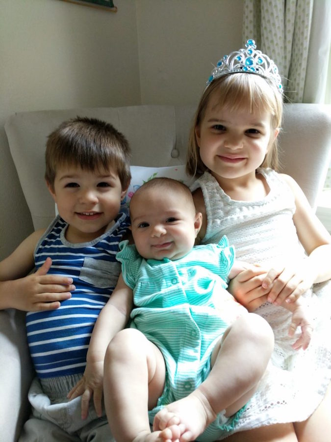 Samuel J. Fetchero W’03's children, Caleb, Eva, and Noelle, smile while seated on a couch.