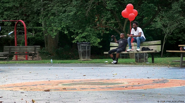 Still from Our Philadelphia, two boys with red balloons sitting on a park bench.