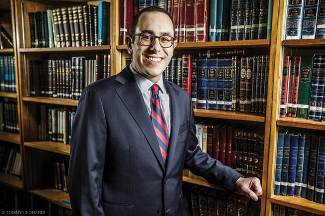 Photo of Rabbi Mike Uram in front of bookshelves at Penn Hillel