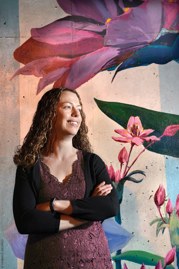 Photograph of Katy Milkman standing in front of a floral mural.