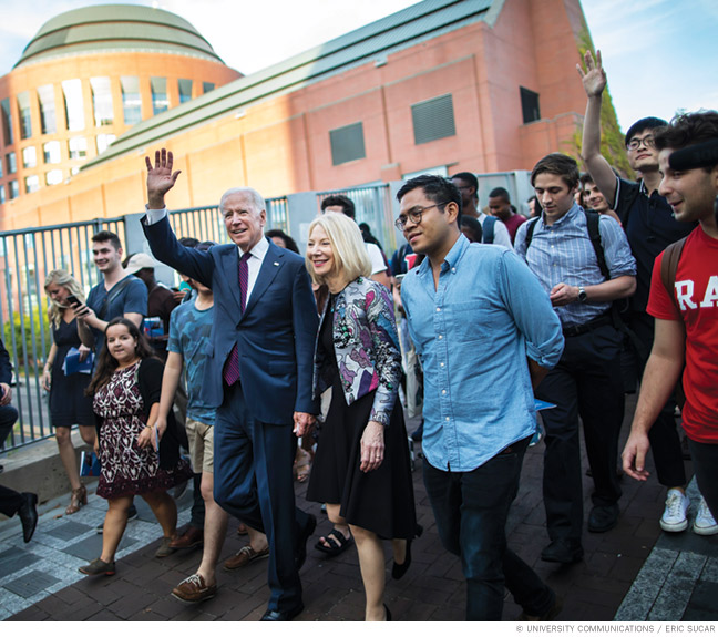 Photo of President Joe Biden with Amy Gutmann on a walk through campus in 2017 with students in tow.