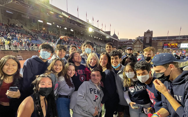 Photo of President Gutmann enjoying a football game with students.